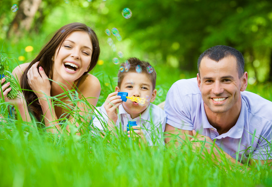 Family of three lying on grass and blows bubbles